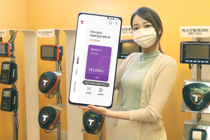 티머니님이 이달에 받은 혜택. 22,000원. 페이머니. 우리 1789. 151,200원 +충전. 티머니페이 모바일 모형을 들고 있는 홍보대사.