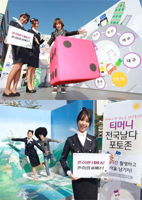 티머니 전국날다 포토존 현수막 앞에서 게임하는 사람과 사진 촬영 피켓을 들고 있는 여자